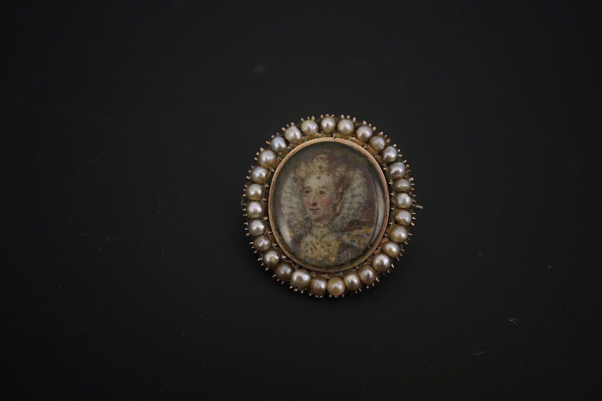 An early 19th century yellow metal and split pearl mounted oval miniature portrait pendant brooch